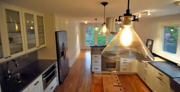 Residential electrician installing modern indoor light fixture in a home in Boise, ID